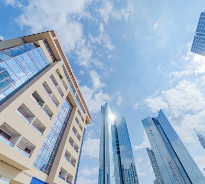 Looking up to high-rise office buildings, skyscrapers, architectures in financial district with blue sky. Smart urban city for business and technology concept background in Downtown Dubai, UAE.